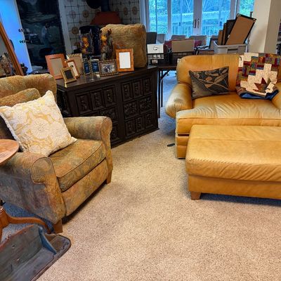 Living room furniture arrangement featuring a gold leather armchair and matching ottoman alongside an upholstered patterned armchair and...