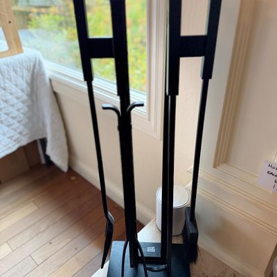 Modern black wrought iron fireplace tool set with stand, including a poker, shovel, and brush.
