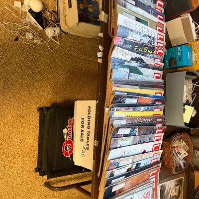 Large collection of vintage Life magazines arranged on a table alongside craft books and various electronics.