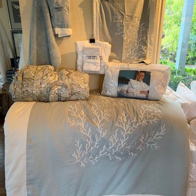 Collection of coastal-themed bedding and linens, featuring a Cuddledown duvet and a light blue coral-embroidered duvet cover with...
