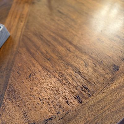 Close-up of a wooden tabletop featuring pieced veneer construction and distressed finish details.