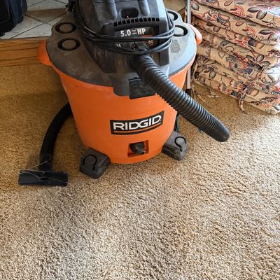Ridgid 5.0 Peak HP wet/dry shop vacuum in orange and black, featuring attached hose and power cord.