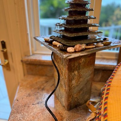 Multitiered natural slate tabletop water fountain featuring a square pedestal base and decorative river stones.