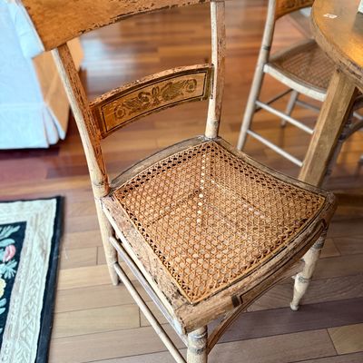 Antique distressed painted side chair featuring a woven cane seat and stenciled back slat detailing.