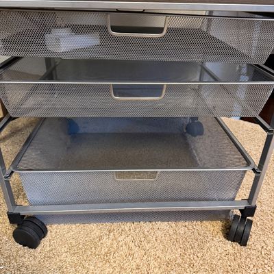 Contemporary silver metal mesh rolling cart featuring three pull-out wire drawers and a faux wood top.