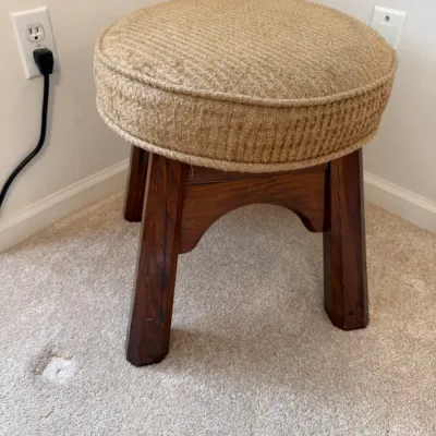 Sale Photo Thumbnail #7: Round upholstered footstool or vanity stool with dark wood legs and beige woven fabric seat.