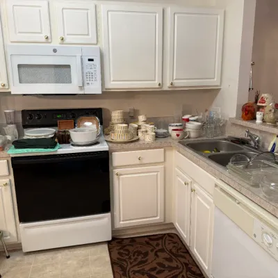 Sale Photo Thumbnail #63: Assorted kitchenware including ceramic dishware, Pyrex glass baking dishes, mugs, and small kitchen appliances displayed on countertops.
