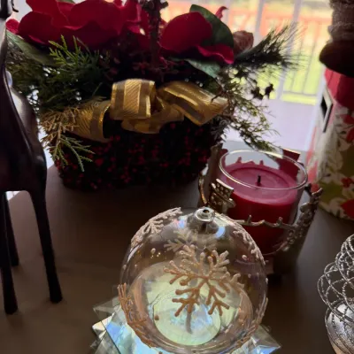 Sale Photo Thumbnail #29: Festive holiday decor arrangement featuring a clear glass snow-themed oil lamp with snowflake detailing, a red jar candle in a decorative holder, and an artificial poinsettia basket center.