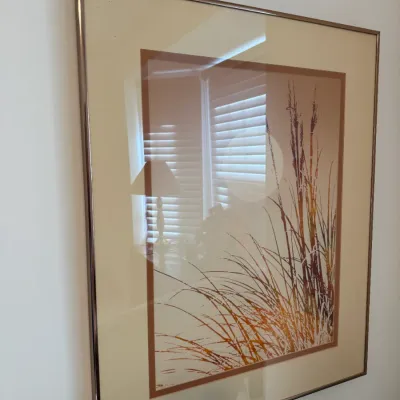 Sale Photo Thumbnail #4: Framed mid-century art print featuring stylized marsh grass in warm earth tones, presented under glass in a metallic frame.