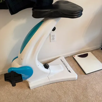 Sale Photo Thumbnail #50: SitNcycle low-impact exercise bicycle with a padded black seat, alongside a digital bathroom scale.
