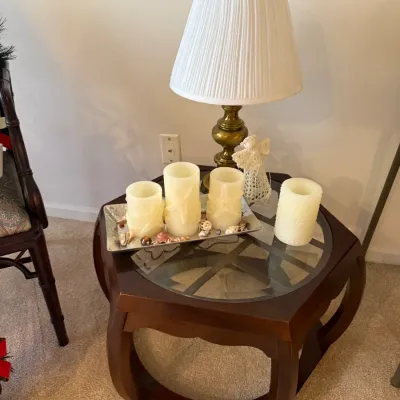 Sale Photo Thumbnail #33: Hexagonal wood side table with a glass top, featuring a small brass table lamp and decorative pillar candles.