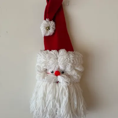 Sale Photo Thumbnail #24: Handmade yarn Santa Claus wall hanging decoration featuring a felt stocking cap, googly eyes, and a red pom-pom nose.