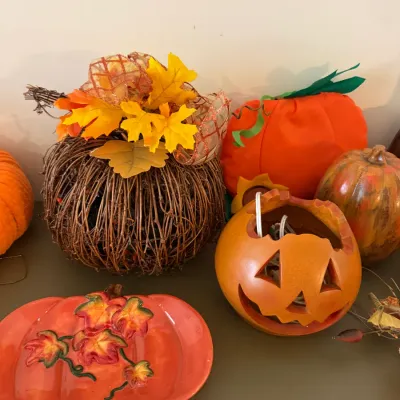 Sale Photo Thumbnail #35: Assortment of autumn and Halloween decorations, including a twig pumpkin, ceramic jack-o'-lantern, and leaf-adorned serving dish.