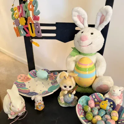 Sale Photo Thumbnail #23: Collection of Easter themed decor, including ceramic bunny figurines, painted egg dishes, a plush white rabbit, and a hanging spring sign.