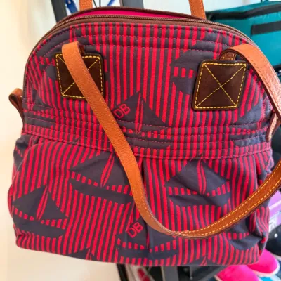 Sale Photo Thumbnail #51: Dooney & Bourke striped fabric handbag featuring a navy sailboat motif and tan leather handles.