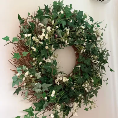 Sale Photo Thumbnail #21: Decorative wall wreath crafted from natural twigs, adorned with artificial ivy leaves and small white floral accents.