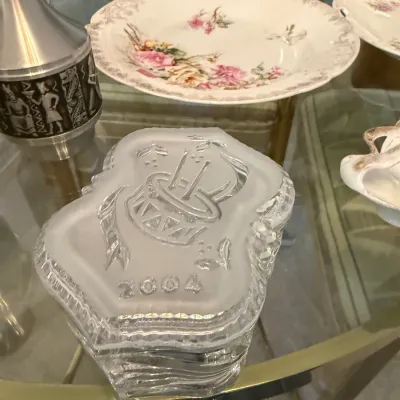 Sale Photo Thumbnail #44: Frosted and clear crystal annual holiday trinket box dated 2004, featuring a drum motif on the lid alongside vintage floral chinaware.