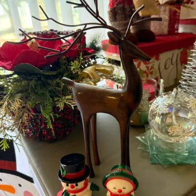 Sale Photo Thumbnail #30: Stylized wooden reindeer figurine with dark metal branch-like antlers, displayed alongside small snowman salt and pepper shakers and other holiday decor.