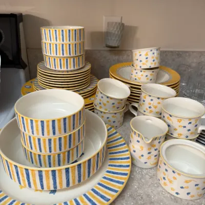 Sale Photo Thumbnail #67: Large ceramic dinnerware set featuring yellow and blue striped borders and small floral motifs, including plates, bowls, teacups, and a creamer and sugar bowl set.