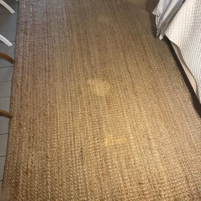 Large woven jute area rug in a natural tan finish, showing a textured chunky loop weave.