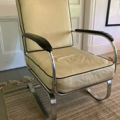 Art Deco style tubular chrome cantilever arm chair with off-white vinyl upholstery and dark piping.