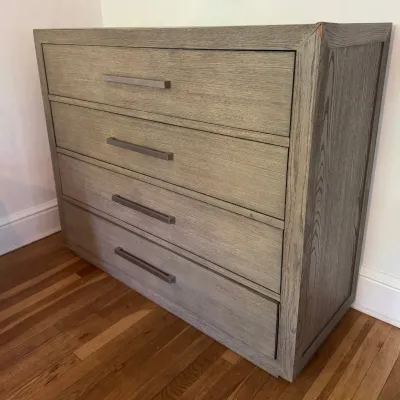Contemporary four-drawer chest featuring a weathered grey oak finish and sleek linear metal bar pulls.