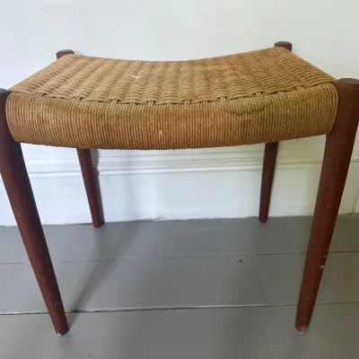 Mid-century Danish modern teak stool featuring a woven paper cord seat and tapered legs.