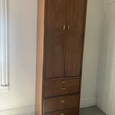 Tall mid-century modern wooden armoire cabinet featuring a top double-door compartment and four drawers with original brass hardware.