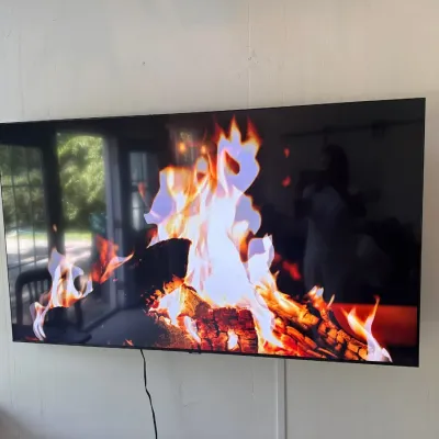 Wall-mounted flat-screen television displaying a digital fireplace, shown in working condition.