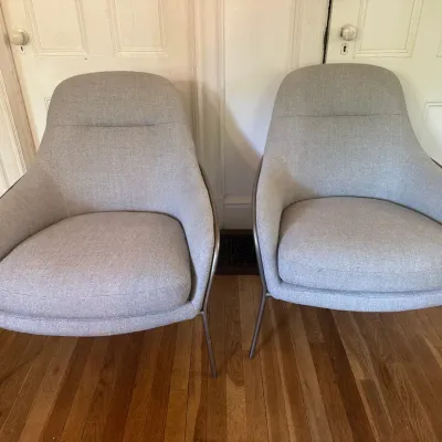 Pair of modern light gray upholstered accent armchairs with thin metal legs.