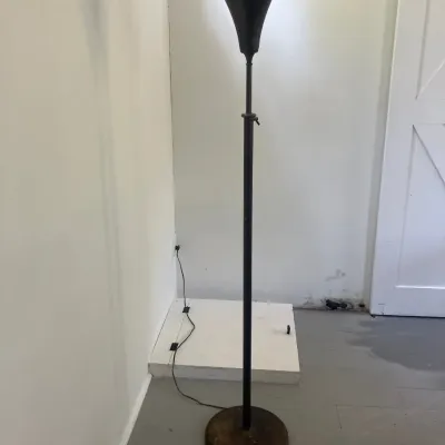 Vintage torchiere floor lamp featuring a black metal trumpet shade and an adjustable-height metal pole on a round base.