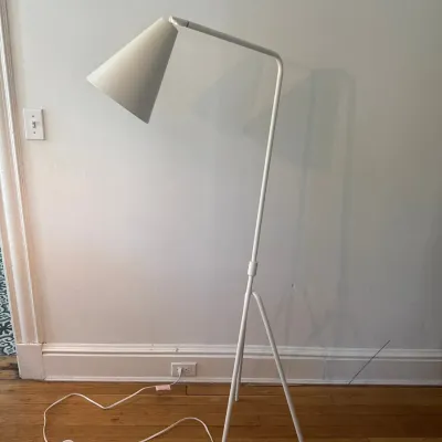 Modern white metal floor lamp featuring an adjustable cone shade, tripod base, and an inline foot switch.