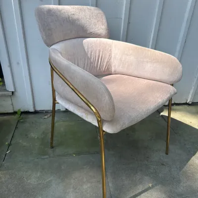 Contemporary armless accent chair with light pink velvet upholstery and a tubular brass frame.