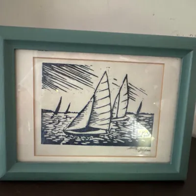 Framed woodcut block print depicting sailboats at sea, signed lower right and presented in a teal wooden frame.