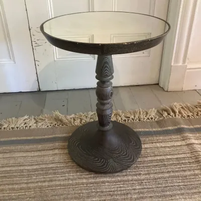 Small round accent table featuring a dark weathered wood turned pedestal base and a mirrored top.
