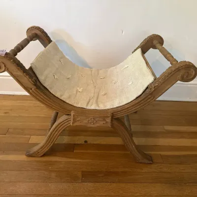 Vintage carved wooden curule bench or vanity stool with a natural linen tufted cushion.
