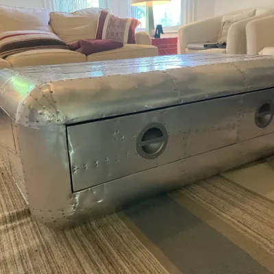 Aviator-style metal coffee table featuring patchwork aluminum panels, exposed rivets, and a large front drawer with recessed handles.