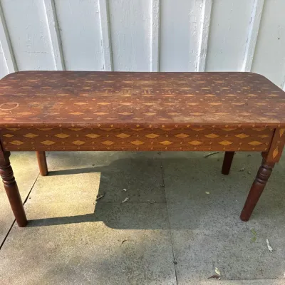 Antique folk art wooden coffee table featuring intricate geometric diamond marquetry inlay, dated 1918 on the tabletop. The piece shows...