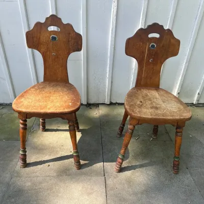 Pair of vintage Bavarian Tyrol-style wooden side chairs featuring carved splats with painted floral motifs and turned legs, showing...