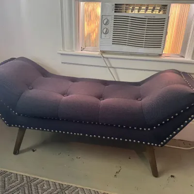 Contemporary tufted bench chaise with purple fabric upholstery, nailhead trim, and tapered wooden legs.