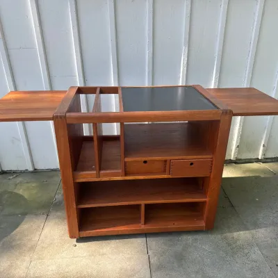 Mid-century Danish teak rolling bar cart featuring drop-leaf side extensions, open shelving, finger-jointed small drawers, and a black...