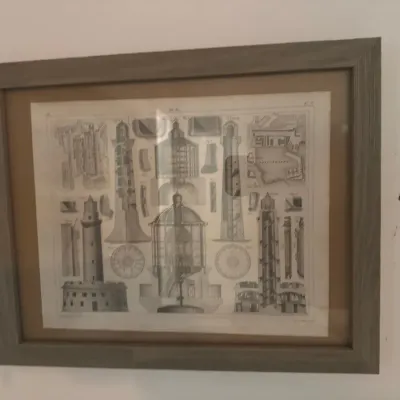 Framed vintage architectural print depicting lighthouse diagrams and cross-sections in a modern wood frame.