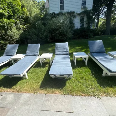 Set of four white-painted wooden outdoor lounge chairs with blue cushions and matching square side tables.
