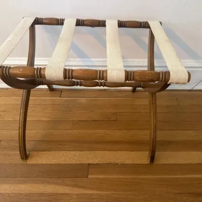 Vintage turned-wood folding luggage rack with white fabric webbing, showing mild surface wear.