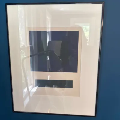 Framed contemporary minimalist geometric print featuring dark blue shapes on an off-white mat, set in a thin black frame.