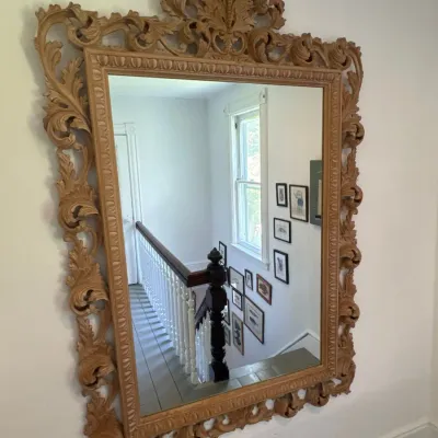 Large ornate wall mirror featuring an intricately carved acanthus leaf frame in a natural wood finish.