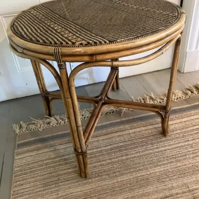 Round vintage bamboo and rattan side table featuring a woven dark-and-light patterned tabletop surface and bentwood cross-brace legs.