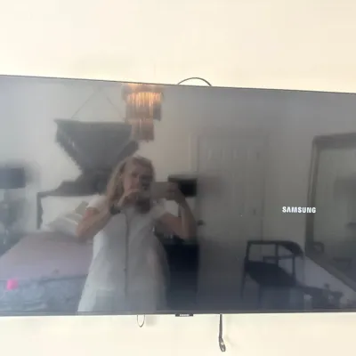 Wall-mounted Samsung flat-screen television with a thin black bezel, showing a reflective screen surface.