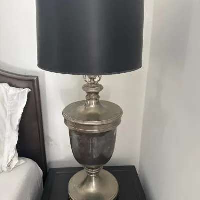 Traditional metal urn-form table lamp with a tarnished silver-tone finish and a black drum shade.