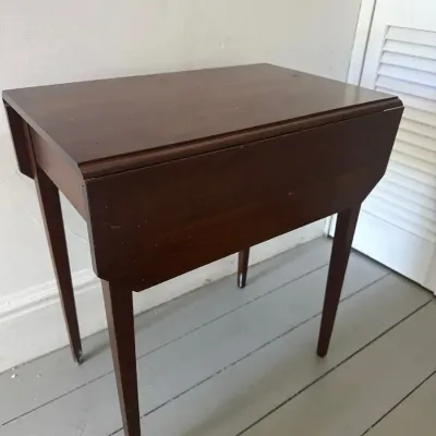 Vintage dark stain wooden drop-leaf side table featuring slender tapered legs and a compact design.